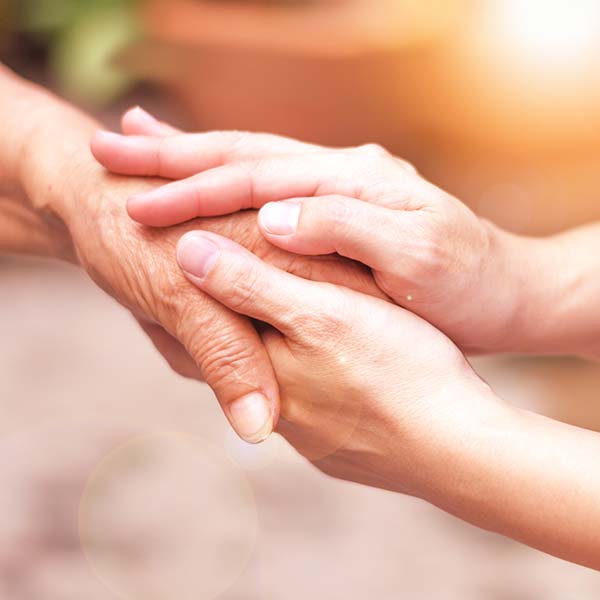 Carer hand holding elder hand in hospice care
